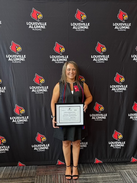a blonde woman poses with an award