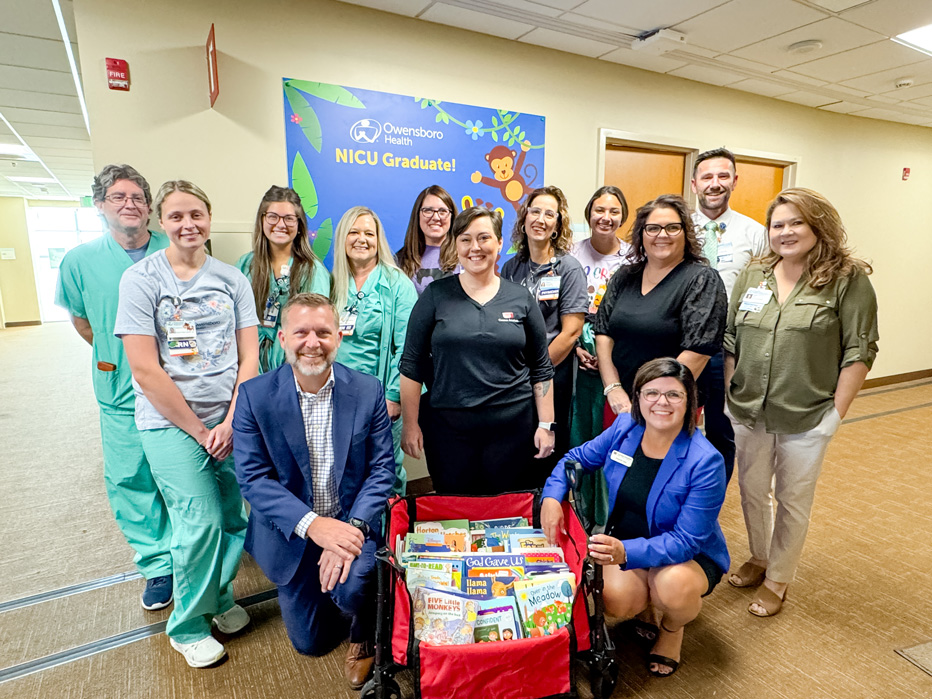 A group of 15 people pose with a container of children's books