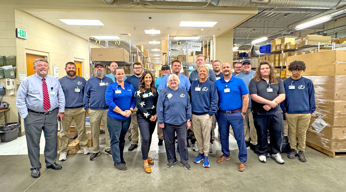 a group of 15 people pose for a photo in a warehouse