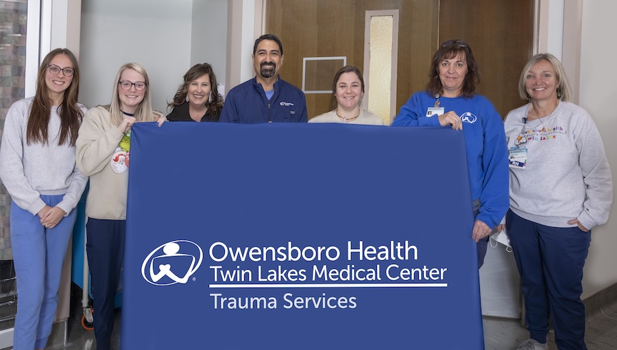 A group of 7 people hold a banner that says Trauma Services