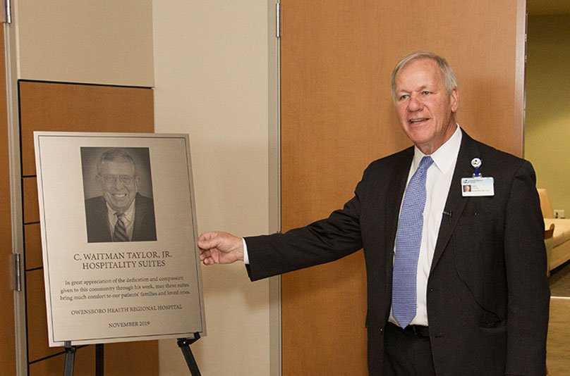 Greg Strahan next to a dedication plaque