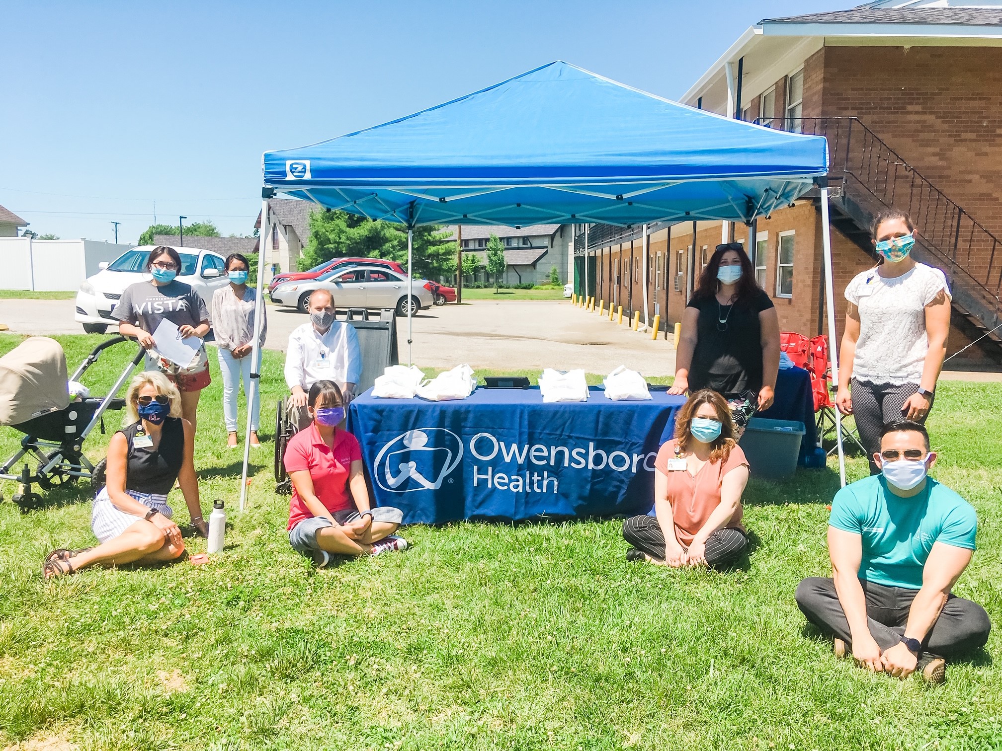 owensboro health team members sit at a tent outside with masks