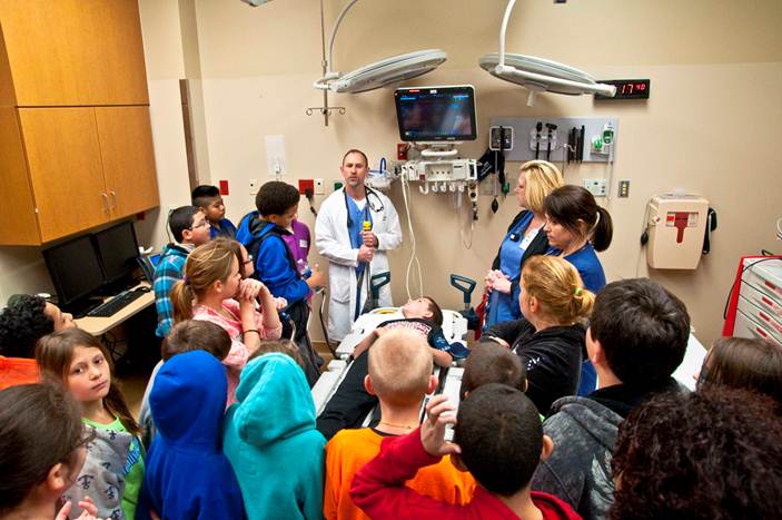 group of middle school students around a hospital bed