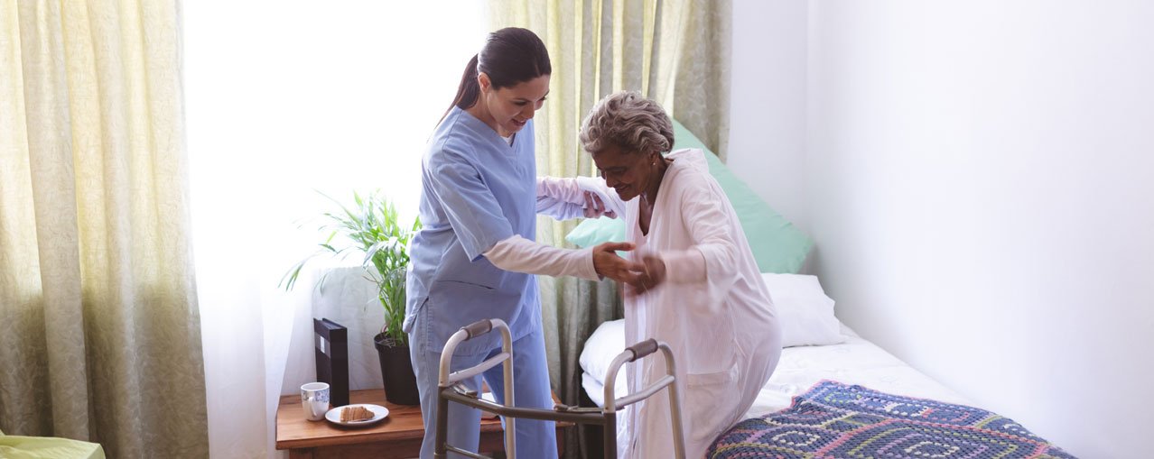 nurse helping patient into bed