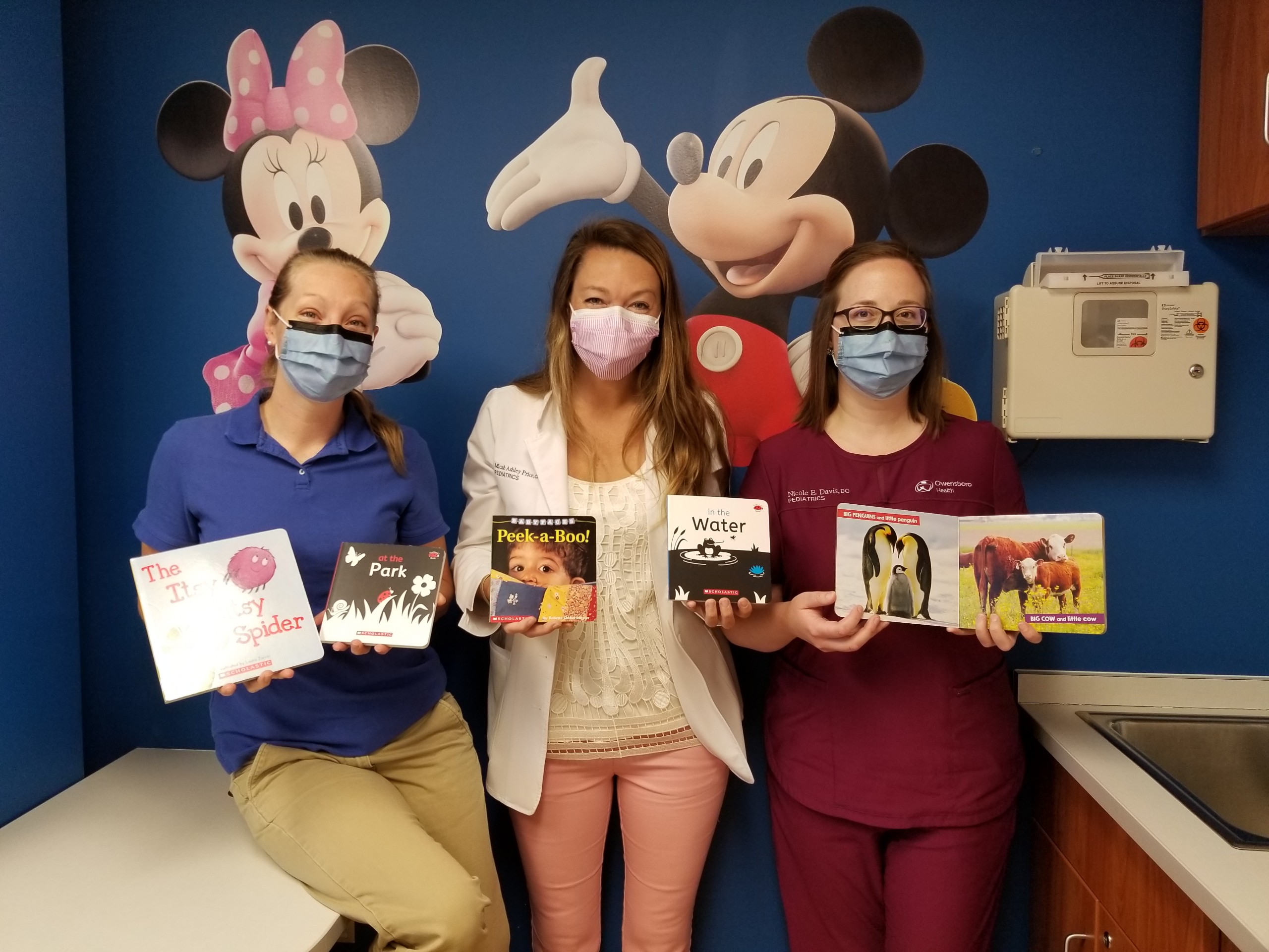 team members hold children's books