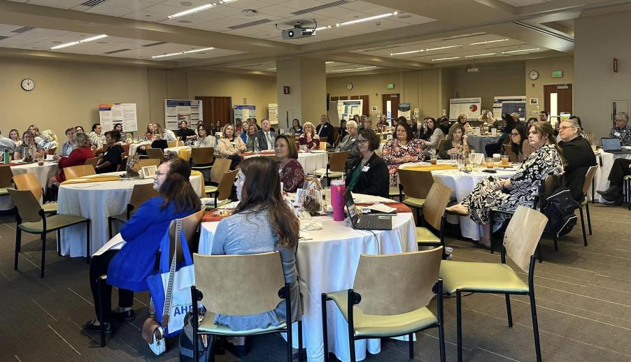 A group of approximately 50 people sitting at tables in a conference room