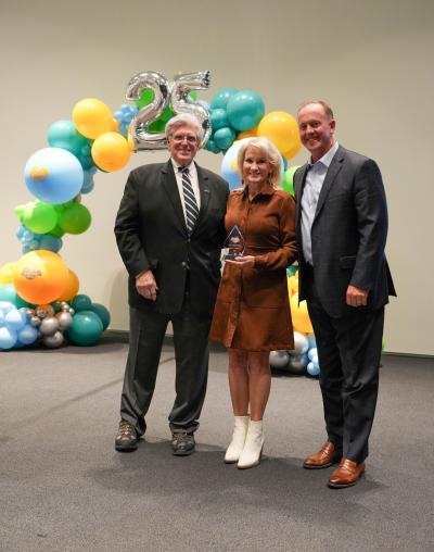 three people holding an award in front of balloons