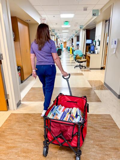 nurse pulling wagon of books down NICU hall