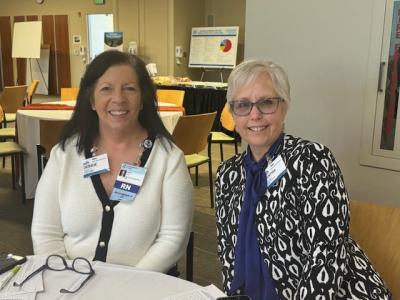 two women sitting next to one another at a table in a conference room