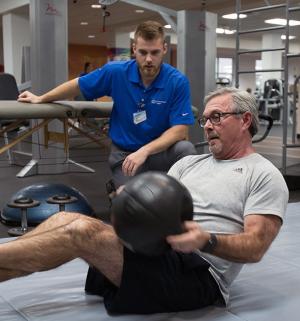 personal trainer and man with exercise ball
